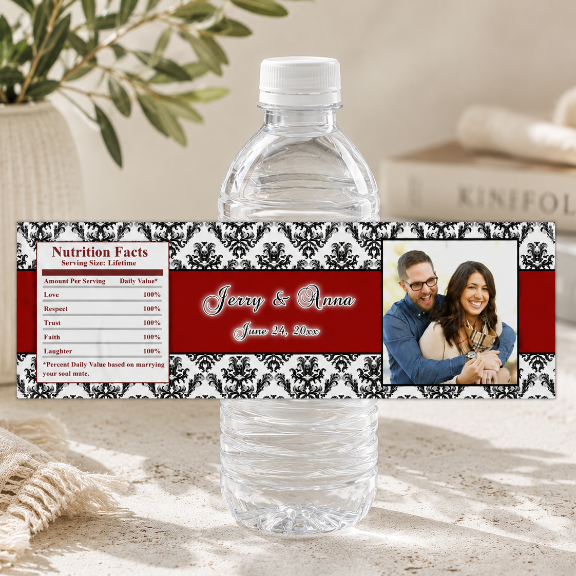 A clear plastic water bottle with a custom printed label. The label features a red and black damask pattern, a sample nutrition facts box, and a photo of a couple.