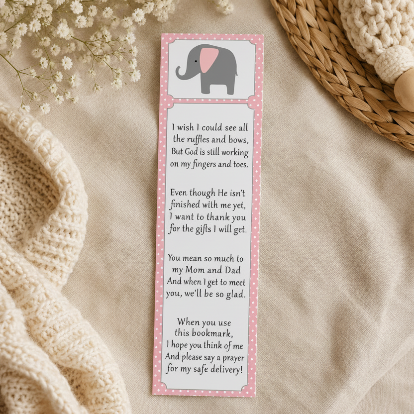 A bookmark with a pink border and an illustration of a small elephant at the top, placed on a beige fabric surface with baby's breath flowers, a woven basket, and a knitted sweater nearby.